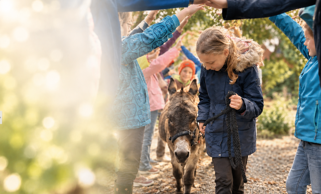 Kinder bilden gemeinsam einen Tunnel für einen Esel bei Buller&Bü